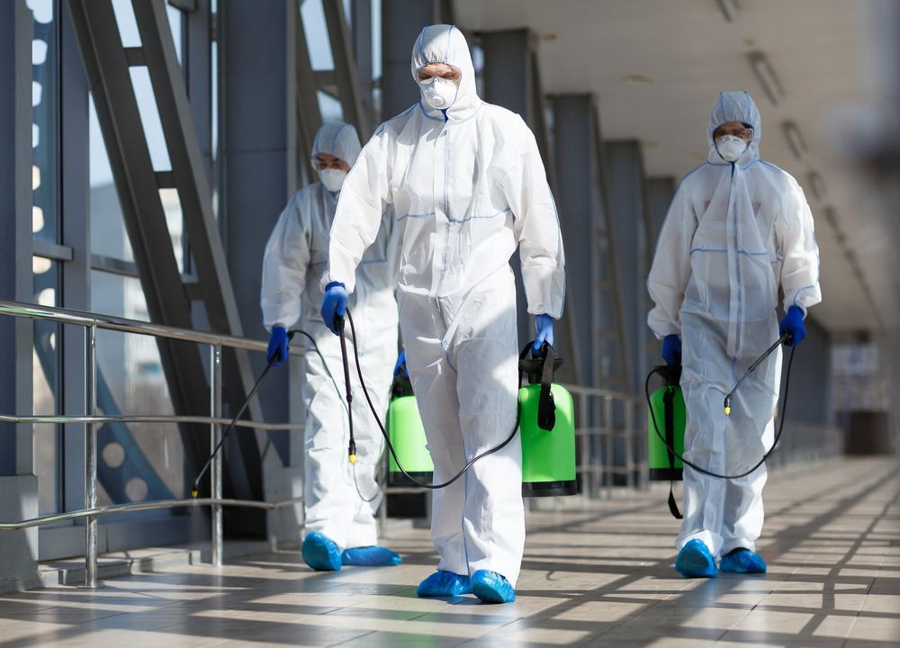 Hogan Cleaning Services crew in protective suits disinfecting a commercial walkway